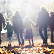 Multigeneration family from behind walking over leaves in the fall.
