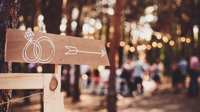 Wooden sign with hand drawn wedding rings and arrow