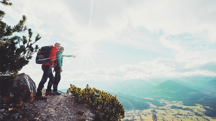 Middle aged couple hiking, overlooking scenic valley.