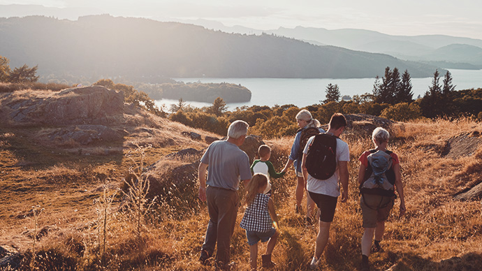 Rear View Of Multi Generation Family Walking On Top Of Hill On Hike