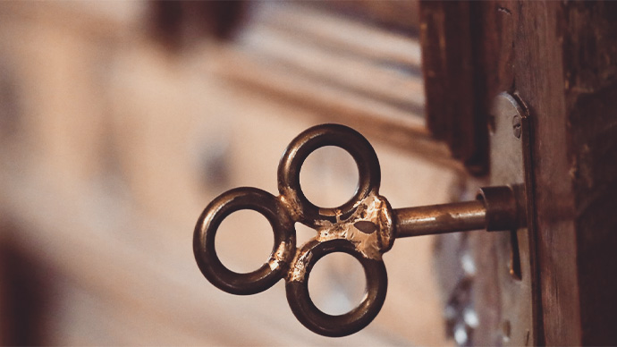 Ornate antique key in keyhole or wooden door