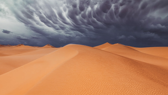 Desert sand dunes, dark clouds and storm on the horizon