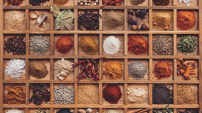 Many colorful, organic, dried, vibrant Indian food, ingredient spices displayed in a wooden compartment tray. Shot directly above, nice color contrast.