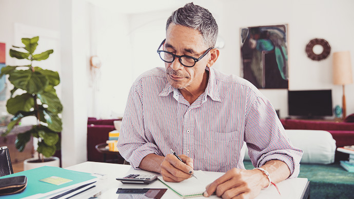 Mature man wearing eyeglasses working on personal finances at home