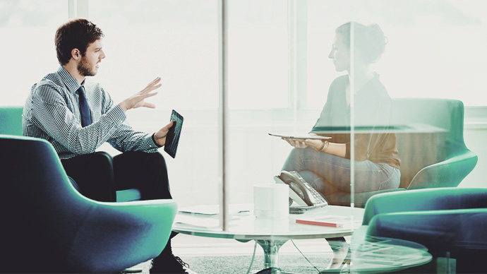 Businessman and businesswoman discussing project on digital tablets during meeting in office