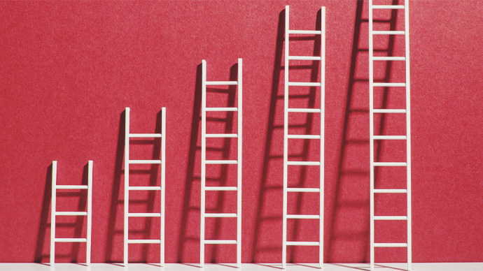 Five ladders of various height leaning against a wall