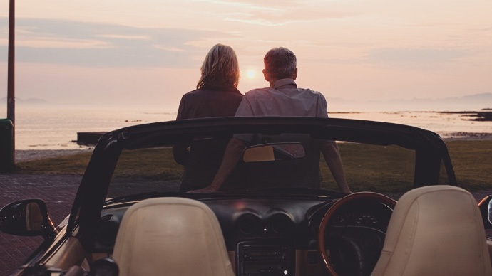 Mature couple admiring sunset in convertible