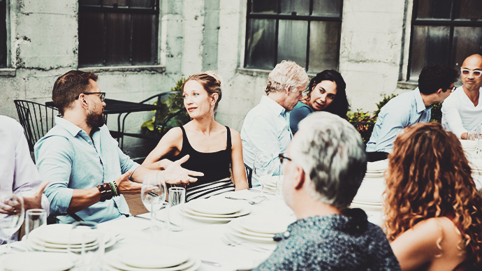 Group of friends seated at table on restaurant patio for celebration dinner