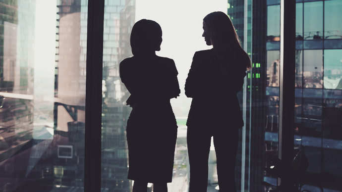 Silhouettes of businesswomen in modern office near window