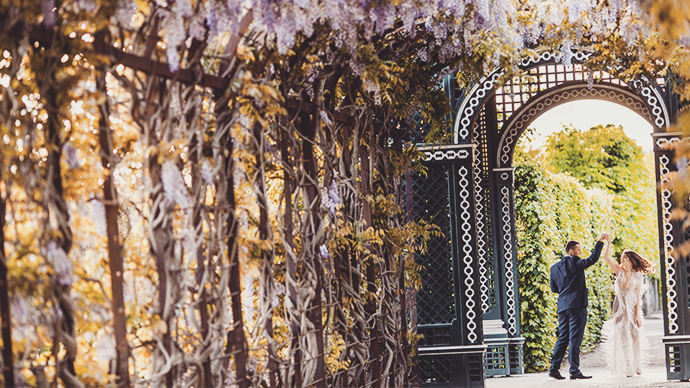 Couple dancing under blooming wisteria in a scenic garden on a sunny day