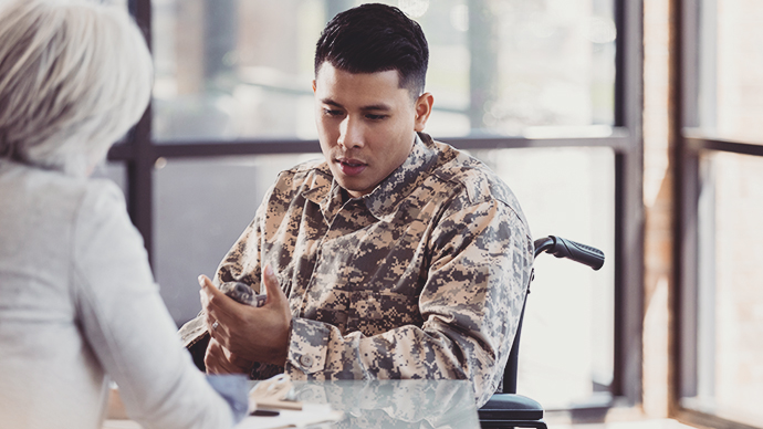 Vulnerable wheelchair-bound male soldier with PTSD discusses hard issues with a caring female mental health professional.