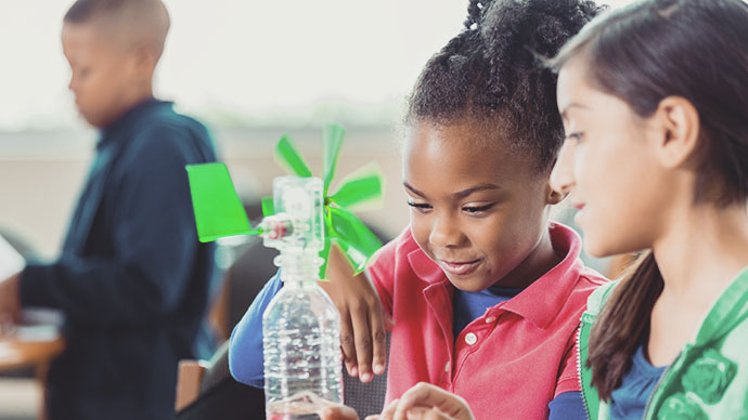 Elementary age girls building a windmill from a water bottle