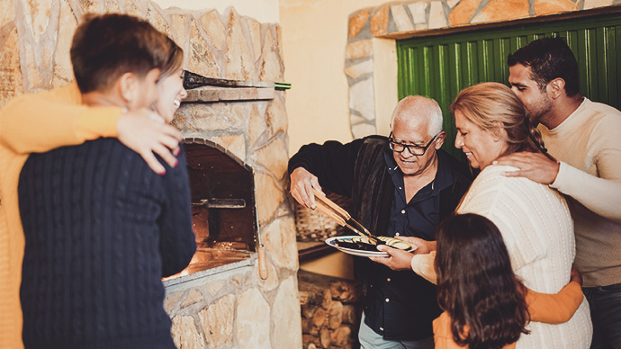 Happy latin family cooking together vegetables on barbecue at home patio