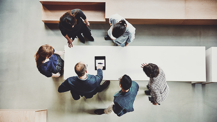 Overhead view of business colleagues discussing project on digital tablet