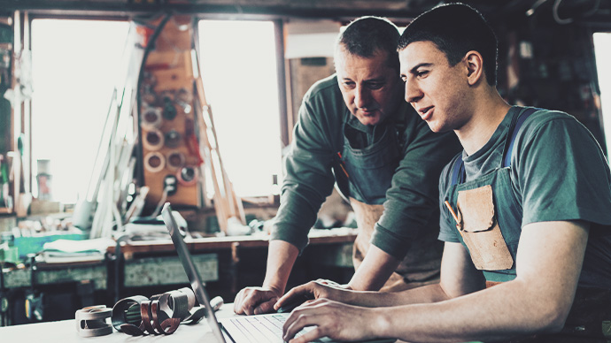 Carpenter and his young assistant working on laptop