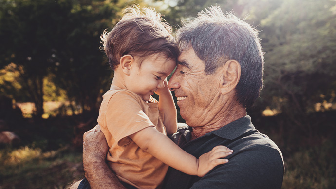 Playful grandfather spending time with his grandson in park on sunny day