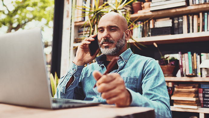 Man in front of a computer talking a cellphone