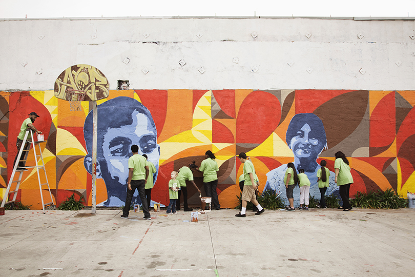 Volunteers painting mural on the wall