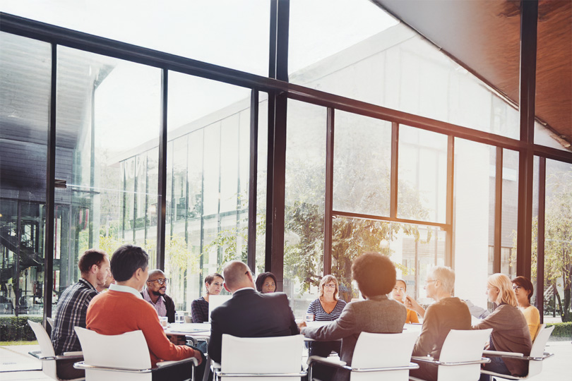 business colleagues sitting at round table in bright glass conference room.