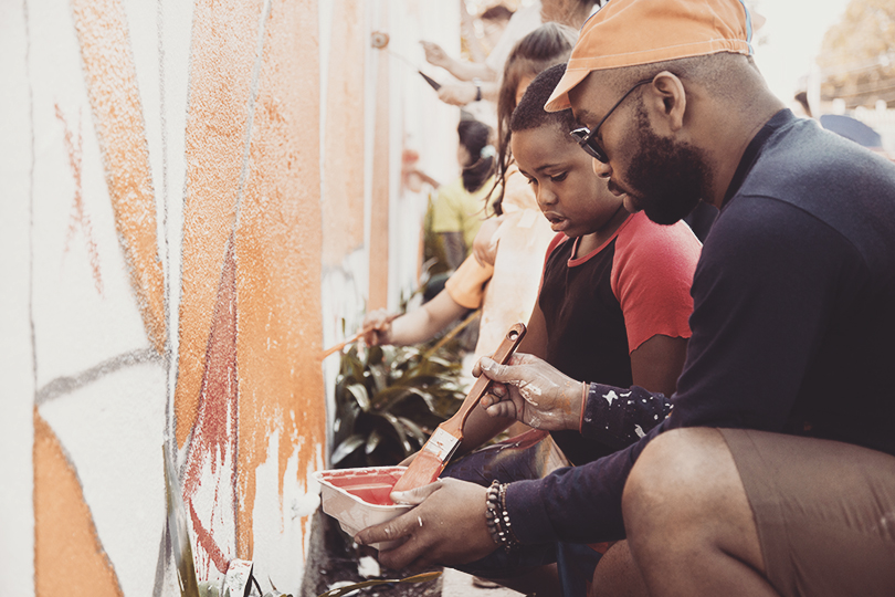Volunteers making art on a concrete wall