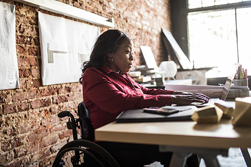Multicultural Investors Businesswoman in wheelchair working at desk