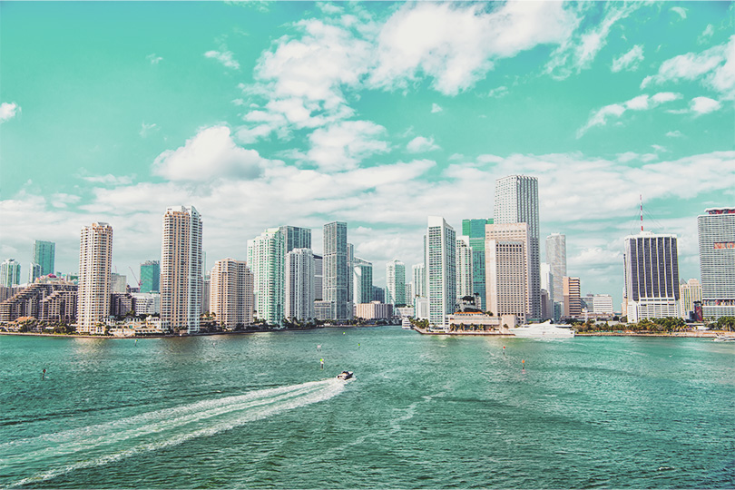 Aerial view of Miami skyscrapers with blue cloudy sky,white boat sailing next to Miami Florida downtown. City skyline