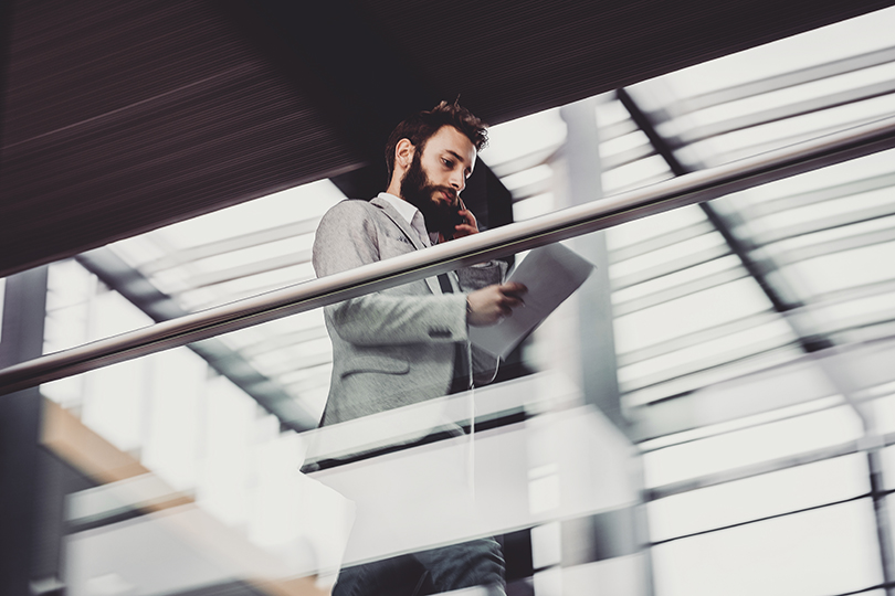 Businessman walking along the hallway, using phone