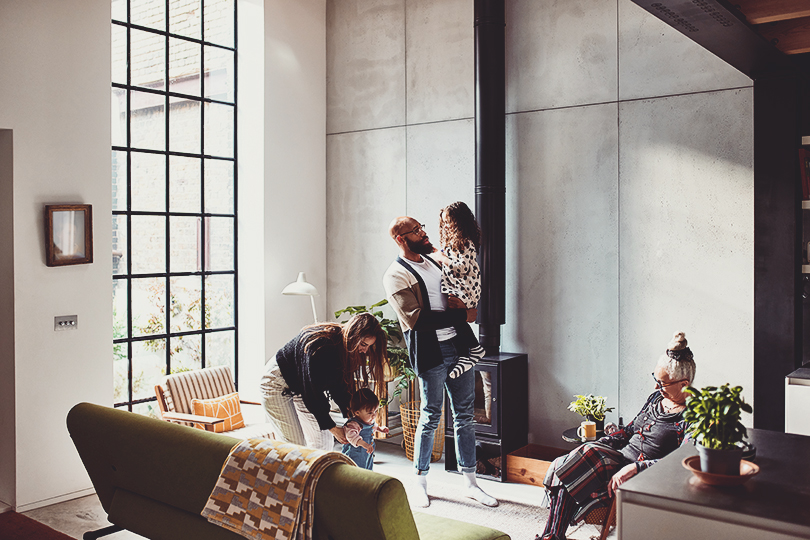 Parents with two children in living room, with grandmother, father holding young girl, mother playing with toddler