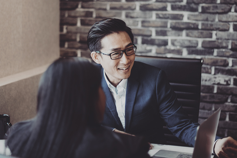 2 asian chinese white collar workers having discussion using laptop