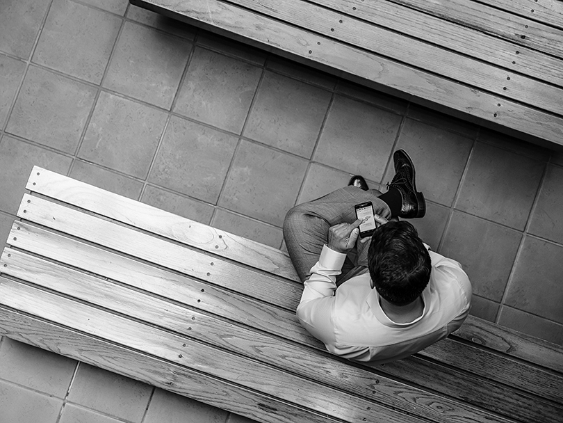 Overhead view of mixed race businessman using cell phone in office courtyard