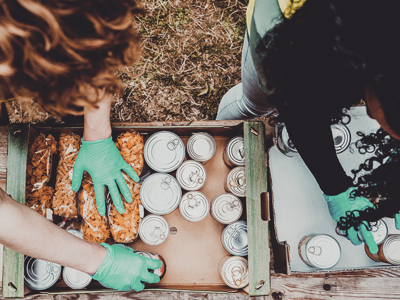 Young diverse women packing boxes at food bank from above