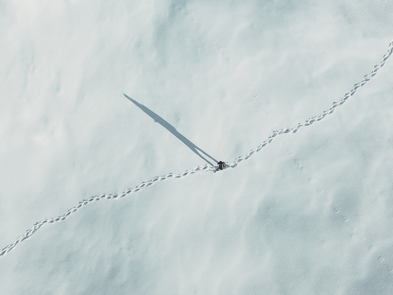 Aerial view on a man hiking through the fresh snow.