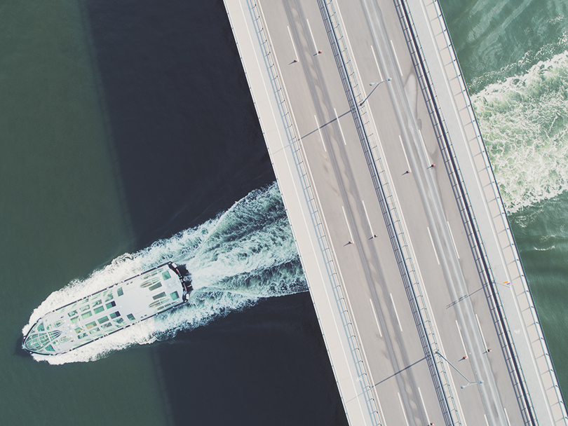 Birdseye view of boat going under a bridge