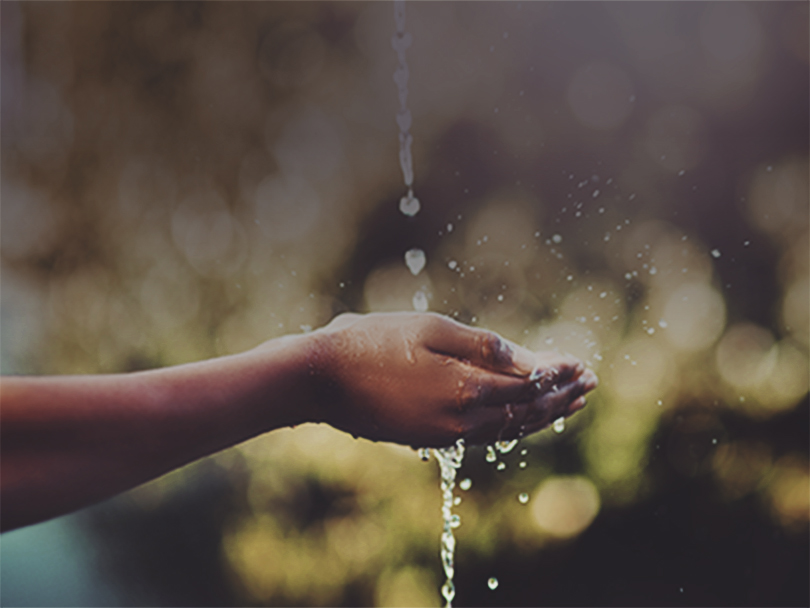 Cropped shot of hands held out to catch a stream of water outside