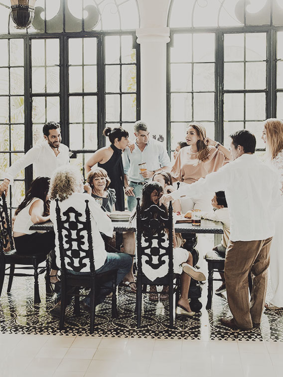 Multigenerational family gathered around dining room table sharing food and drinks during party