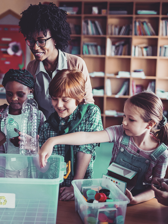 Make an Impact Close up of a teacher the kids in the classroom about recycling and saving the environment