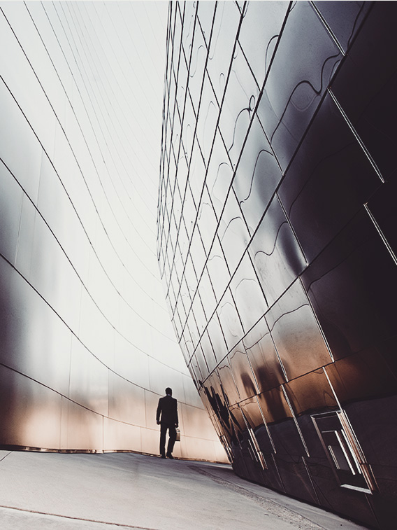 man walking along abstract wall of windows