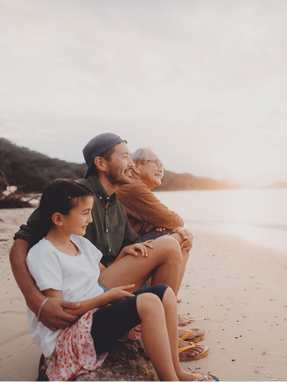 Extended family sitting on the beach smiling